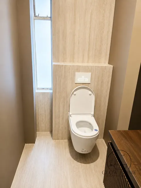 Drewnopodobne płytki na ścianie za WC podwieszanym w wąskiej łazience
